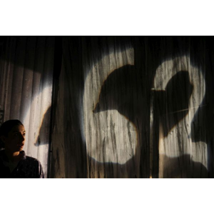 une femme regarde une lumière projetée sur un drap flottant. Il semble y avoir écrit 662.