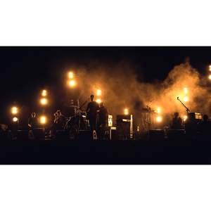 Un groupe de rock debout sur scène, dans le noir sous la lumière jaune