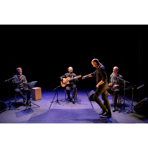quatre musiciens sur scène : une guitare, deux chanteurs et un tambour